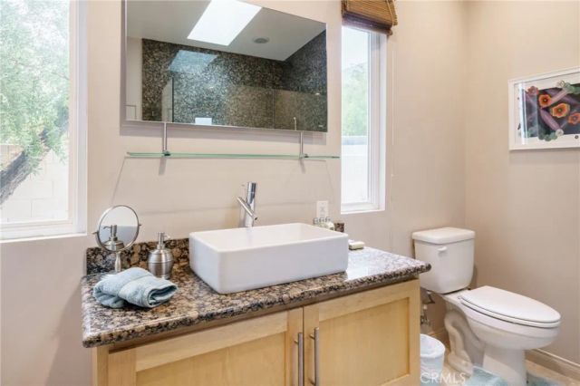 a bathroom with a granite countertop sink and a toilet