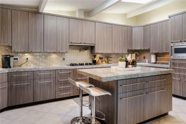 a kitchen with stainless steel appliances granite countertop a table chairs sink and cabinets