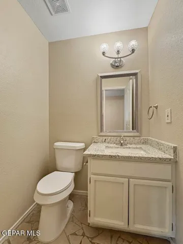 a bathroom with a granite countertop toilet sink and mirror