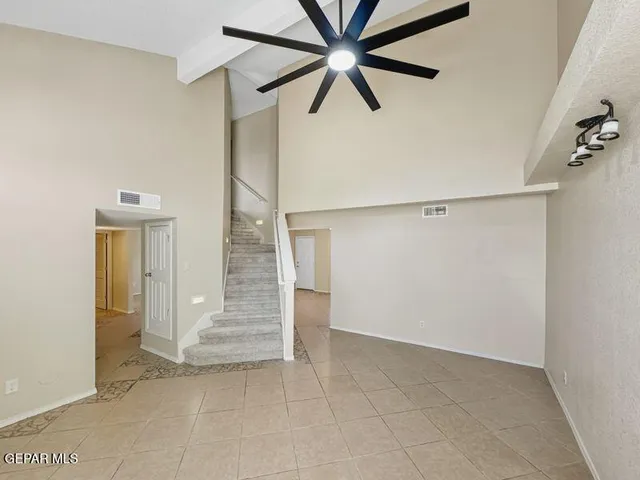 an empty room with a hallway and a ceiling fan