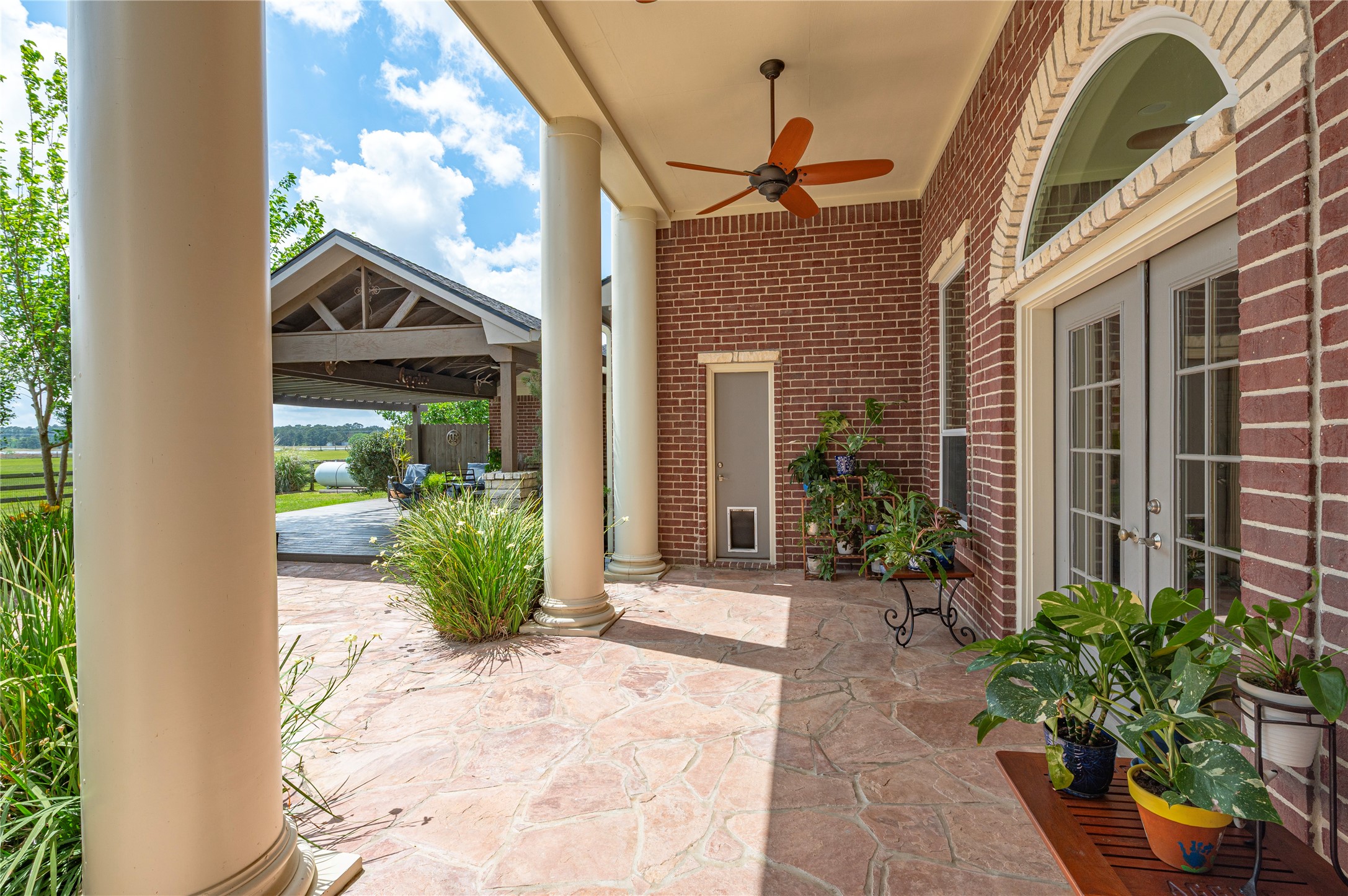 8211 Deats Lane Dickinson, TX 77539 - Photo 20 of 50 Spacious 40-foot back covered patio and extensive outdoor entertainment area provides views of wide-open pastures and mature trees scattered throughout the property, further enhancing the sense of space and serenity.