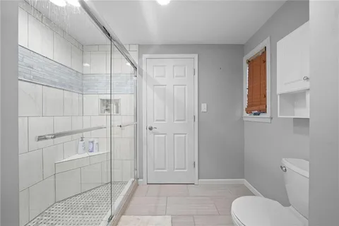a view of a hallway with wooden floor and a bathroom