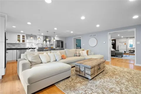 a living room with a couch and a dining table with wooden floor