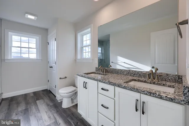 a bathroom with a granite countertop sink toilet and mirror