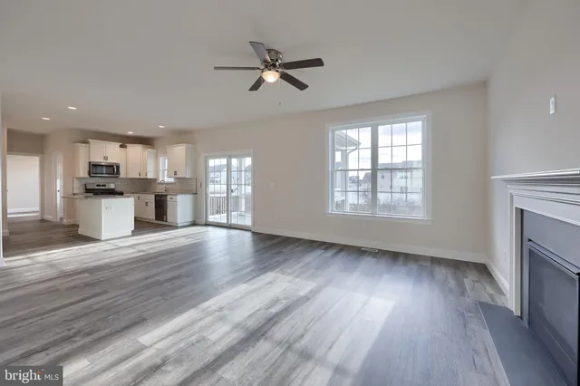 an empty room with wooden floor a ceiling fan and windows
