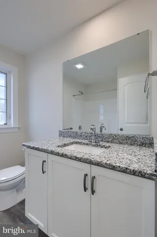 a bathroom with a granite countertop sink a toilet and a mirror
