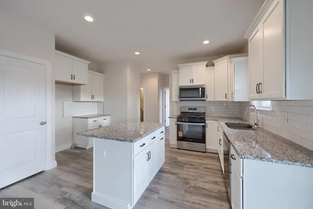 a large kitchen with granite countertop a sink and stainless steel appliances