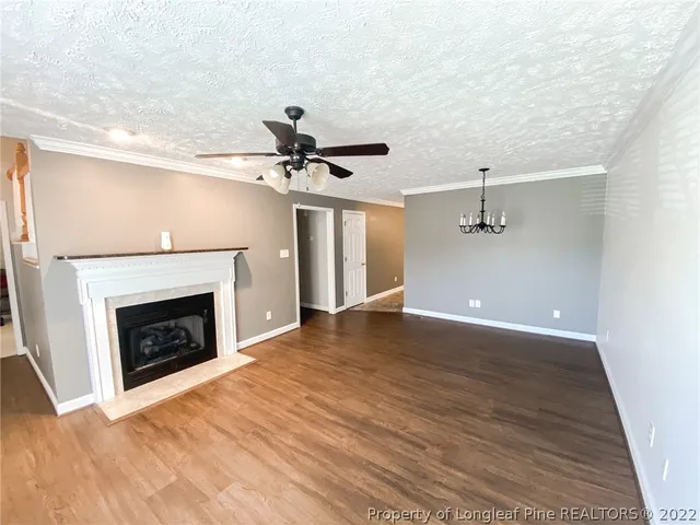 a view of an empty room with wooden floor fireplace and a window