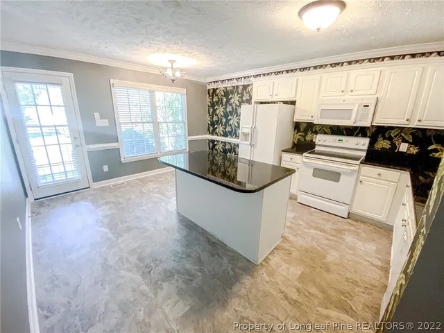 a large white kitchen with granite countertop a sink a stove a refrigerator a window