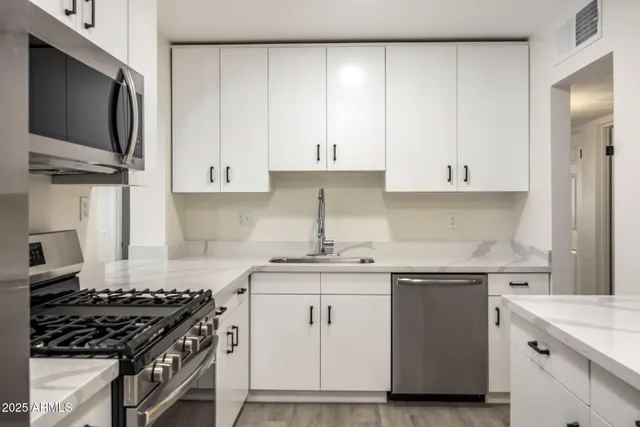 a kitchen with white cabinets and appliances