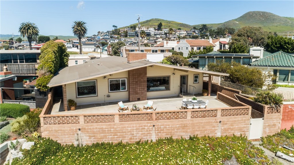8 Ocean Front Lane, Unit AB Cayucos, CA 93430 - Photo 29 of 36 a view of a white house with a swimming pool and lawn chairs under an umbrella