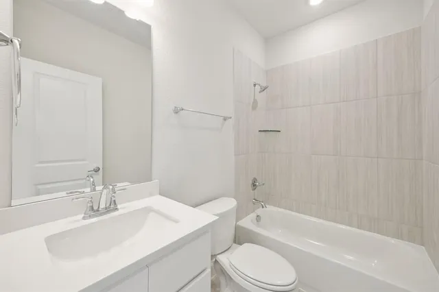a bathroom with a bathtub shower sink vanity mirror and toilet