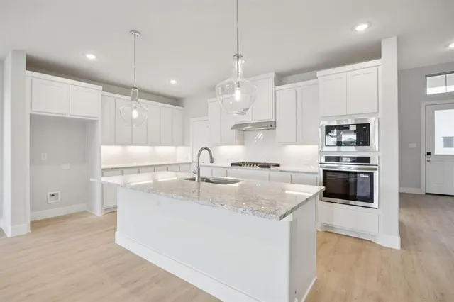 a large kitchen with granite countertop a sink a counter top stainless steel appliances and cabinets