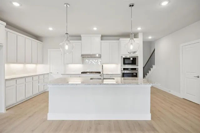 a large kitchen with stainless steel appliances kitchen island a large counter top and a wooden floors