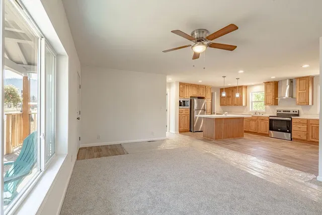 a view of a livingroom with a ceiling fan & kitchen view