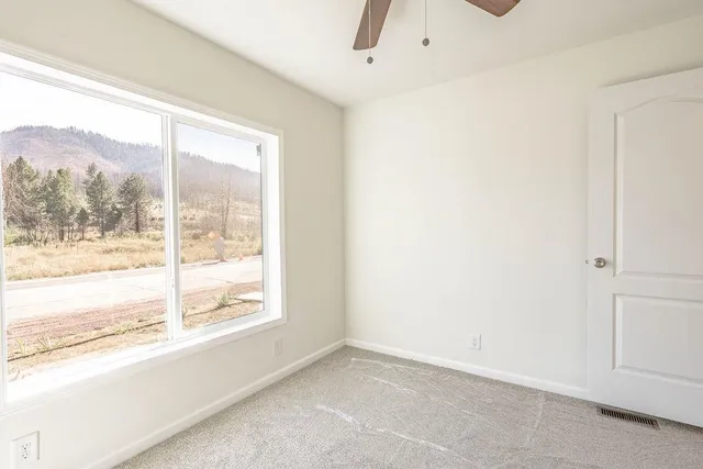 an empty room with a window and a ceiling fan