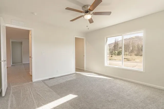 an empty room with closet and a ceiling fan