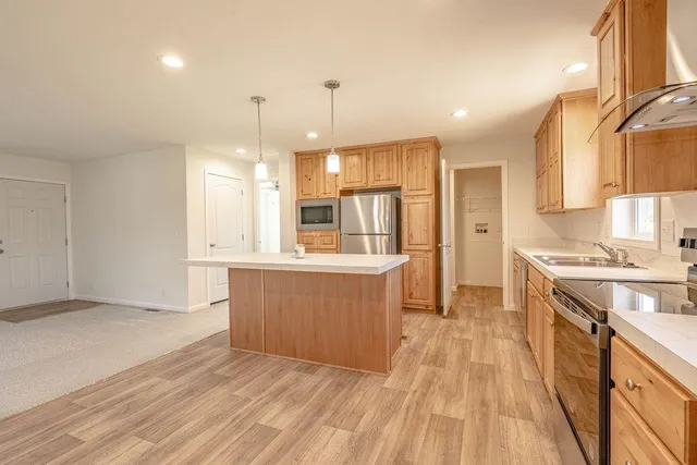 a large kitchen with granite countertop a large counter top a sink stainless steel appliances and cabinets