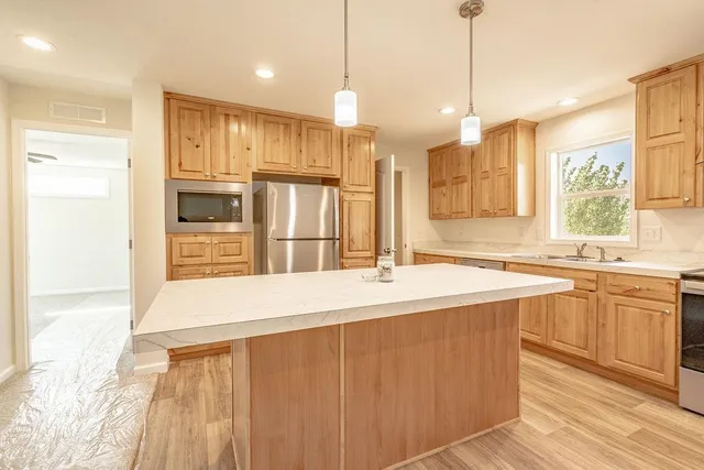 a large kitchen with kitchen island a sink a center island and stainless steel appliances