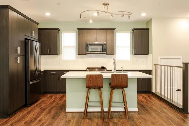 a kitchen with stainless steel appliances kitchen island granite countertop a sink refrigerator and microwave