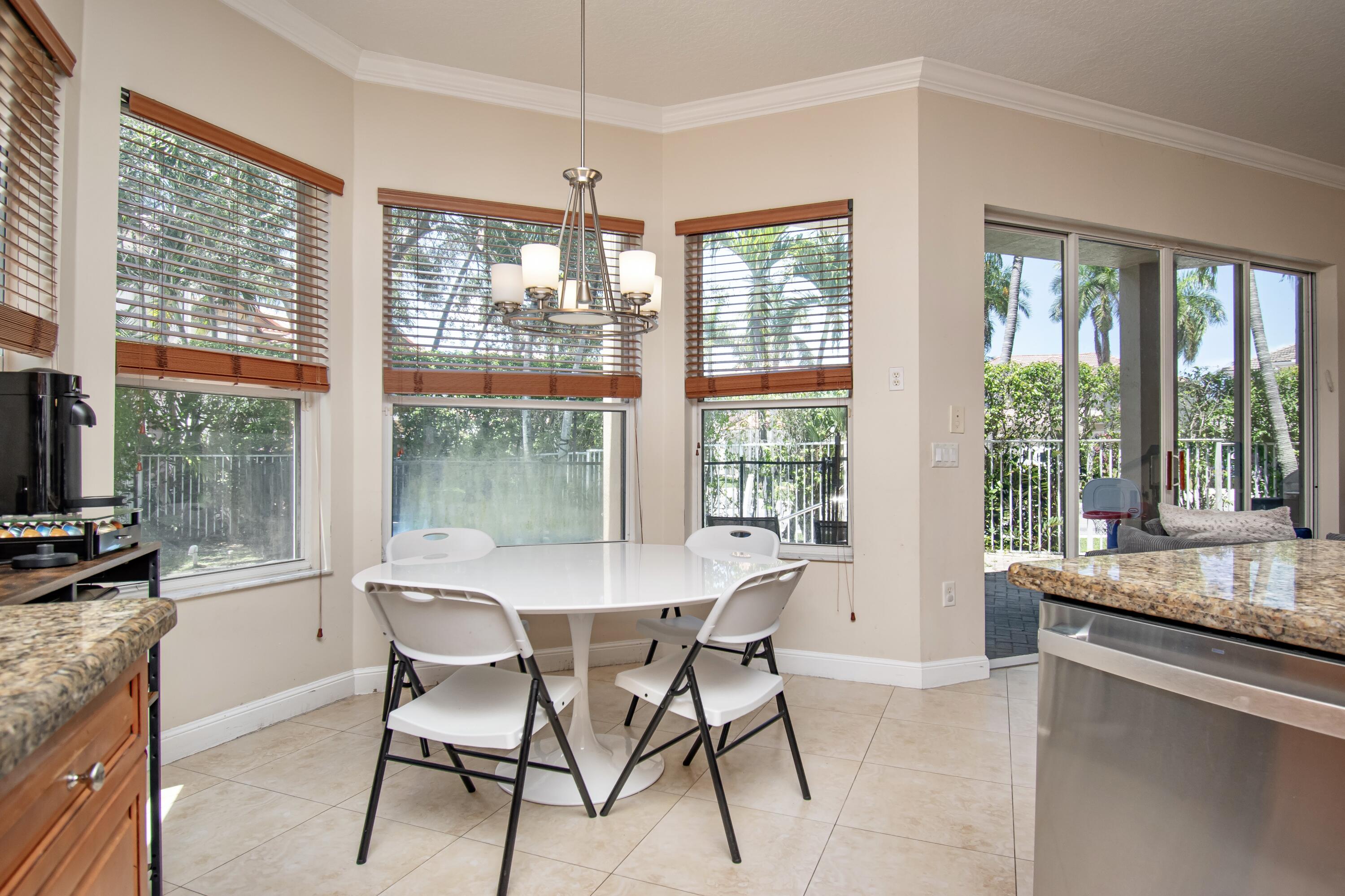 9851 Palma Vista Way Boca Raton, FL 33428 - Photo 18 of 33 a dining room with wooden floor a chandelier a glass table and chairs