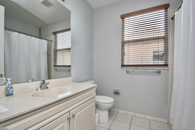a bathroom with a granite countertop sink toilet a mirror and a window