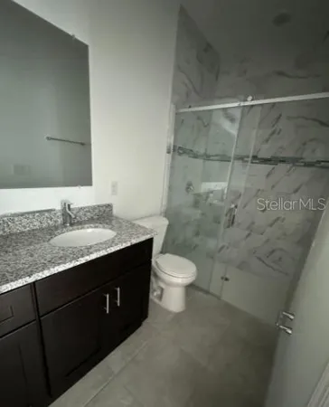 a bathroom with a granite countertop sink toilet and shower