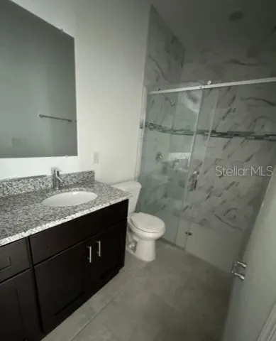 a bathroom with a granite countertop sink toilet and shower