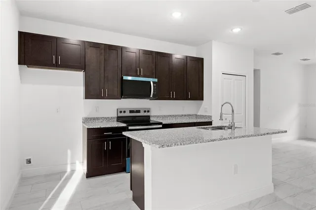 a kitchen with stainless steel appliances granite countertop a sink stove and refrigerator