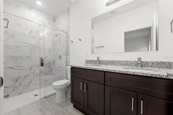 a bathroom with a granite countertop sink toilet and shower