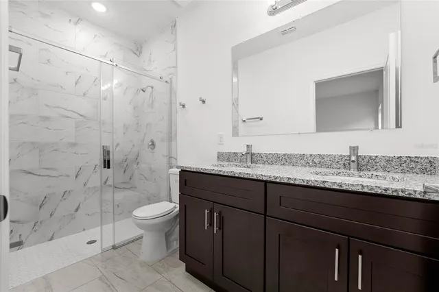 a bathroom with a granite countertop sink toilet and shower