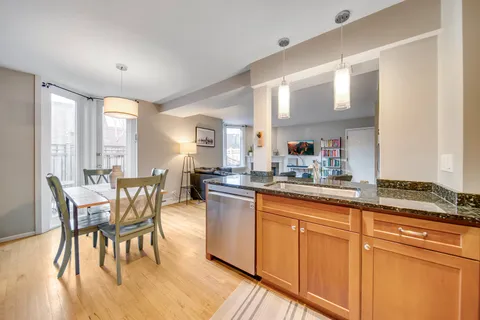 a kitchen with stainless steel appliances granite countertop dining table chairs cabinets and wooden floor
