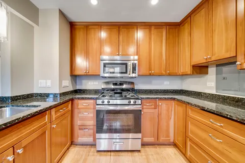 a kitchen with granite countertop a stove a sink and a microwave