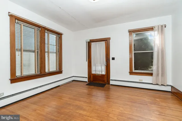 a view of an empty room with glass door and wooden floor