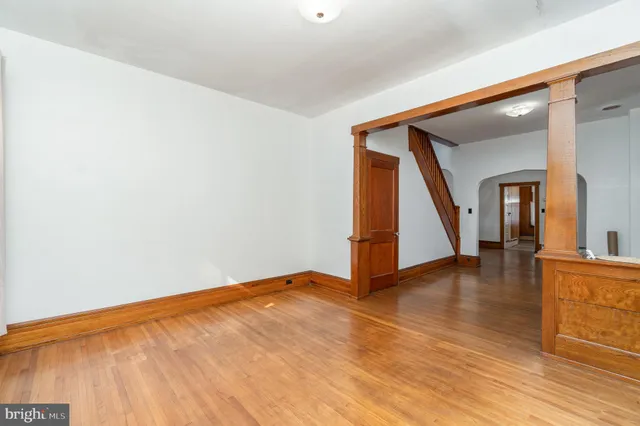 a view of an empty room with wooden floor and stairs