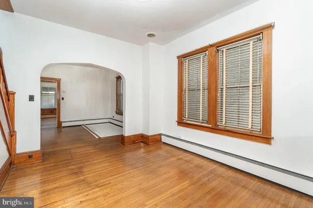 a view of an empty room with window and wooden floor