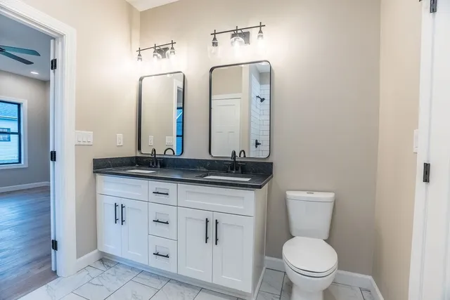 a bathroom with a granite countertop toilet sink and mirror