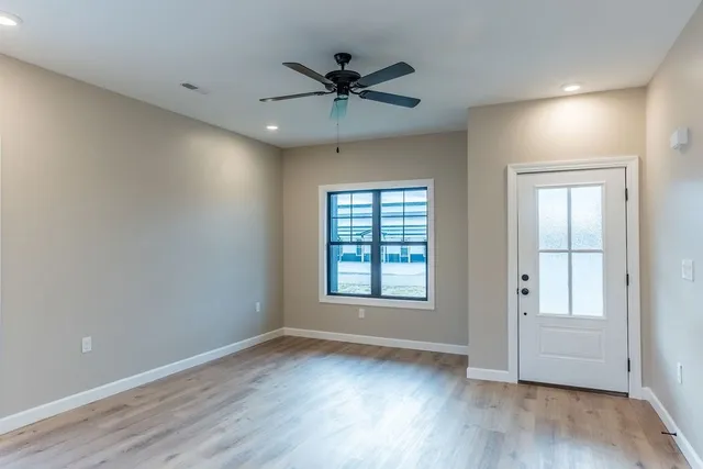 a view of an empty room with wooden floor and a window