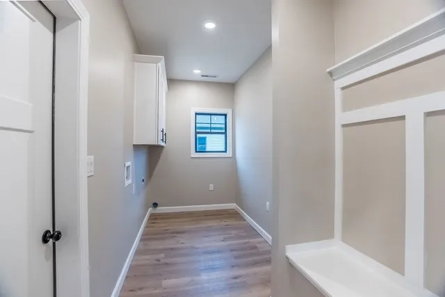 a view of a hallway with wooden floor and a bathroom
