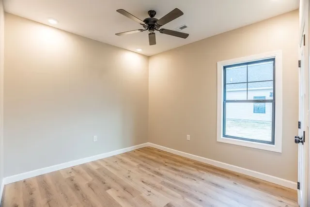 an empty room with windows and fan