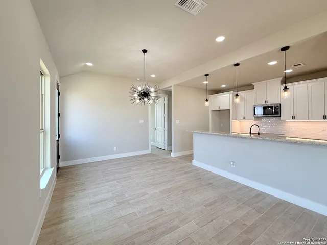 a view of large kitchen with stainless steel appliances kitchen island a sink dishwasher a refrigerator and a wooden floor