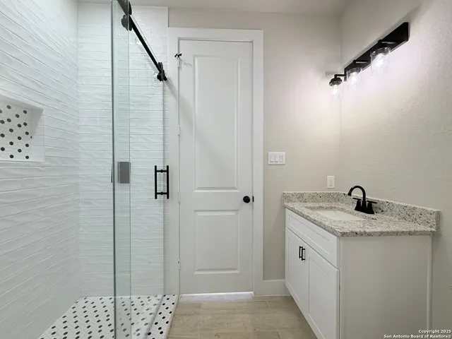 a bathroom with a granite countertop sink a toilet and shower