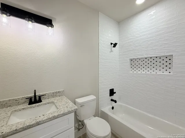 a bathroom with a granite countertop sink toilet and shower