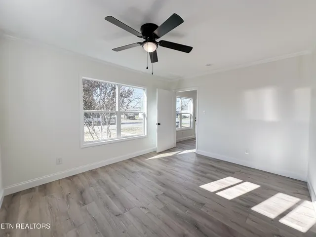 a view of empty room with wooden floor and fan