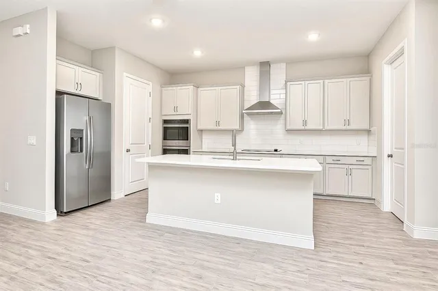 a kitchen with kitchen island a sink a stove a refrigerator and white cabinets