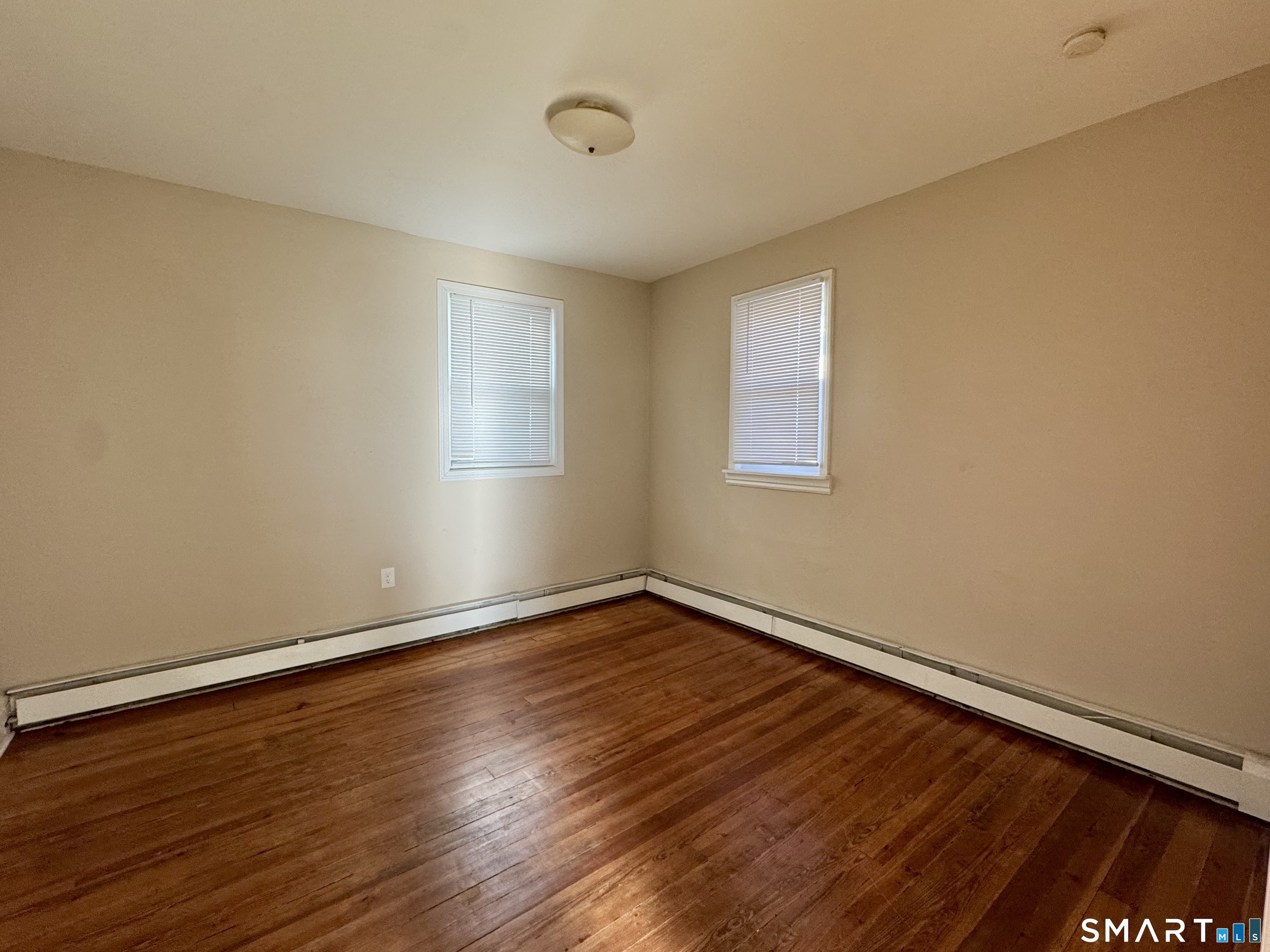 182 Sheridan Street, Unit 2 Bridgeport, CT 06610 - Photo 5 of 9 a view of an empty room with wooden floor and a window
