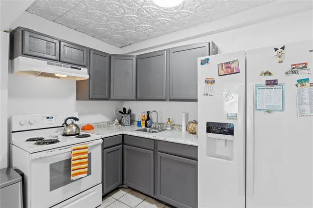 a kitchen with stainless steel appliances a refrigerator a sink and white cabinets