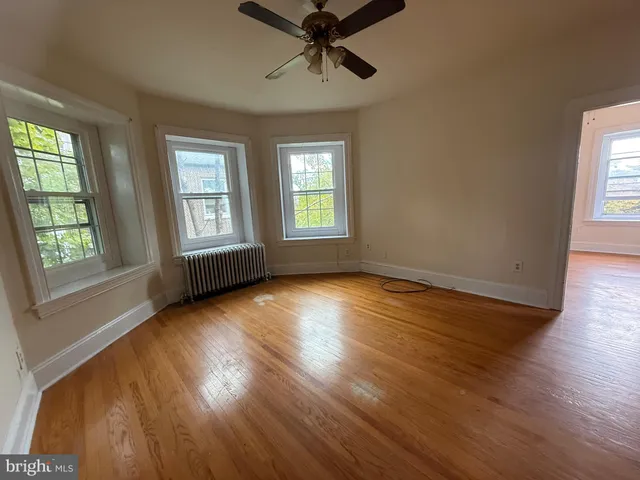 a view of empty room with wooden floor and fan