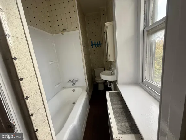 a bathroom with a bathtub a sink and a large mirror next to a window