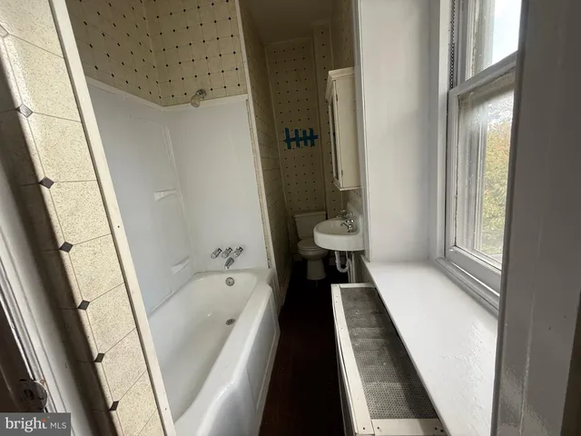 a bathroom with a bathtub a sink and a large mirror next to a window